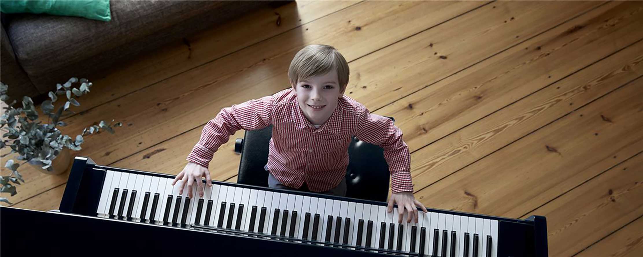 Aufgeweckter Junge spielt am Yamaha b Klavier